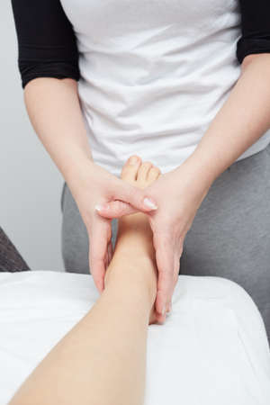 Close-up of female hands doing foot massageの写真素材
