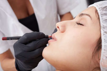 Cosmetologist making permanent makeup on woman's faceの写真素材