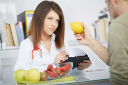 conceptual photo of a female nutritionist with fruits on the deskの写真素材