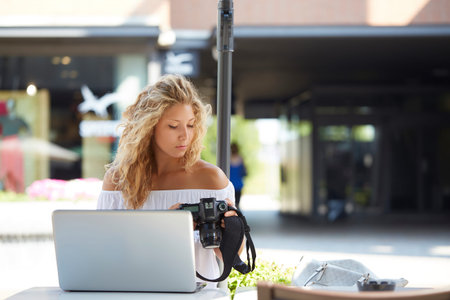woman outdoors using a digital reflex to take pictures and check on her laptop what she made