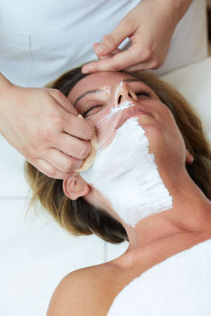Beautiful woman with clear skin getting facial mask at salonの写真素材