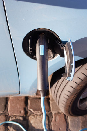 Green electric car at charging station with power outlet