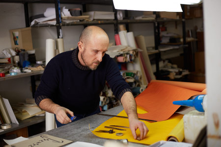 craftsman cutting leather with cutter  in workshop