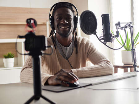 afroamerican happy young male recording audio blog in headphones microphone broadcasting at home ...の写真素材