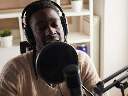 afroamerican happy young male recording audio blog in headphones microphone broadcasting at home ...の写真素材