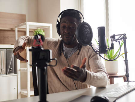 afroamerican happy young male recording audio blog in headphones microphone broadcasting at home ...の写真素材