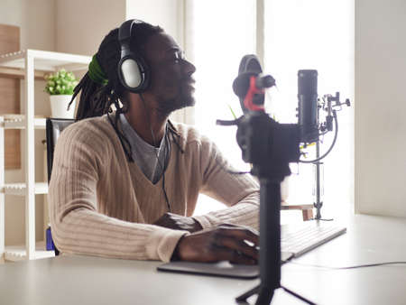 afroamerican happy young male recording audio blog in headphones microphone broadcasting at home ...の写真素材