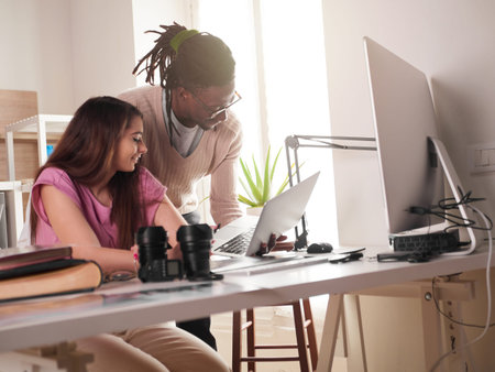 Young couple of photographers working with laptop at the working place with two computers in the...