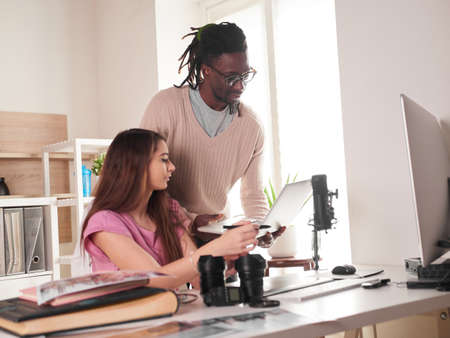 Young couple of photographers working with laptop at the working place with two computers in the studioの写真素材