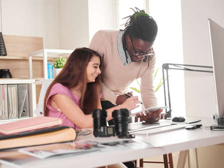Young couple of photographers working with laptop at the working place with two computers in the studioの写真素材
