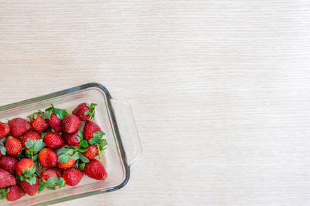 glass bowl with strawberries on a wooden texture backgroundの写真素材