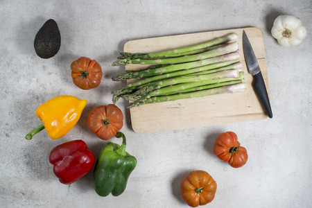 Fresh vegetables on table tomatoes garlic asparagus avocado green pepper red pepper yellow pepper. Platter and knife ready to preparing the salad. Raw food to cook healthy and diet.の写真素材