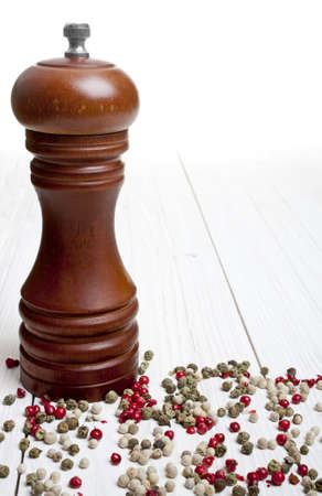 pepper-mill with peppercorns on white wooden backgroundの写真素材