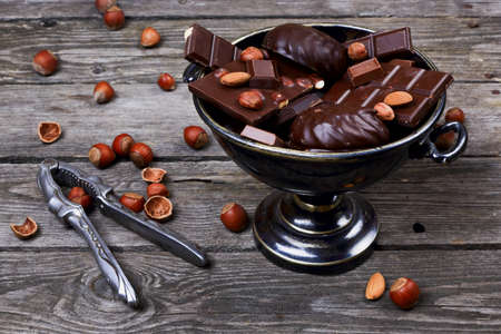 Vase with chocolate, nuts and nutcracker on a gray wooden backgroundの写真素材