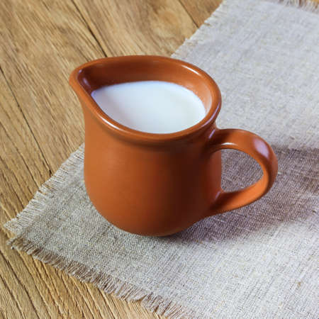 Milk in a jug on the wooden table close upの写真素材