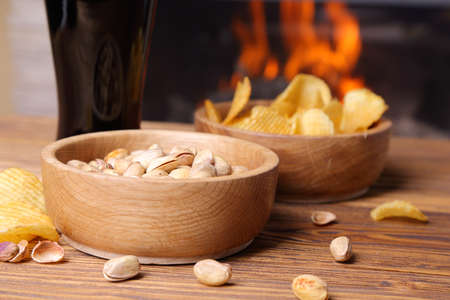 Pistachio, chips and beer on a background of a burning fireplaceの写真素材