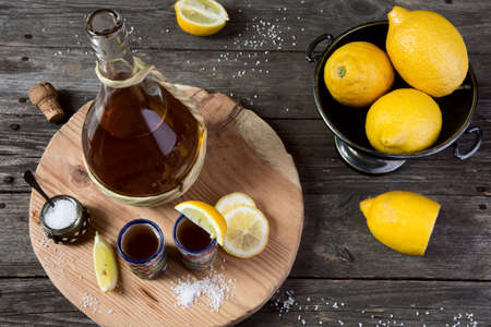Tequila with a lemon and salt on a wooden tableの写真素材