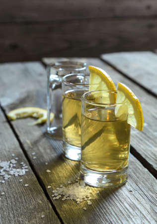 Glasses of tequila with lemon and salt on a wooden table,selective focusの写真素材