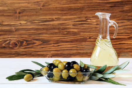 Olives and olive oil on a white table on wooden background, copy spaceの写真素材