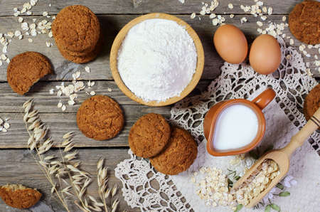 Oatmeal cookies and ingredients for its preparation on a wooden table, top viewの写真素材