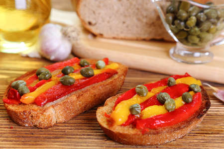 Bruschetta with grilled peppers and capers on a wooden table, selective focusの写真素材