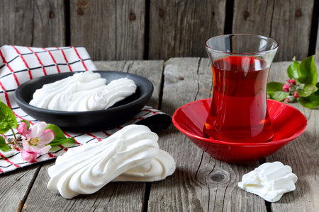 Meringues and cup of tea on a gray wooden table