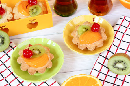 Tartlets with fruits and tea on a white wooden table