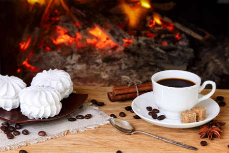 Cup of coffee with spices and marshmallows on a background of a burning fireplaceの写真素材