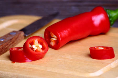 Pod of red chili peppers cut across on a cutting boardの写真素材
