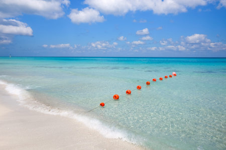 Chain of orange buoys against the blue sea and white beach sand - the concept of tourism and beach...