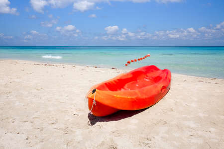 Orange canoe on a sandy beach against the sea, concept of outdoor activitiesの写真素材