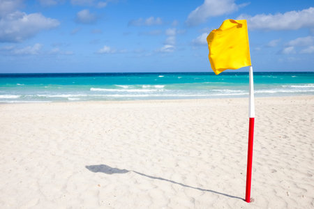 Yellow flag on a sandy beach against the ocean, Cuba, Varadero, concept of tourism and recreation