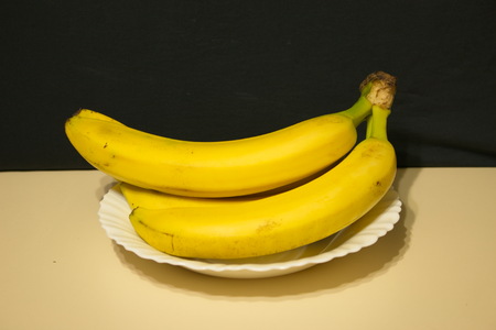 Bunch of bananas light table dark background in a plateの写真素材