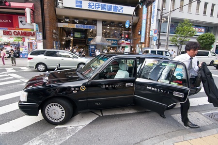 TOKYO, JAPAN, JULY 5: unidentified person out of a taxi in Shinjuku district on July 5, 2011 in Tokyo, Japan. Tokyo is estimated that there are around 35,000 taxi drivers are divided into 33 different companies. Typically, taxis are Toyota Crown Comfort.のeditorial素材
