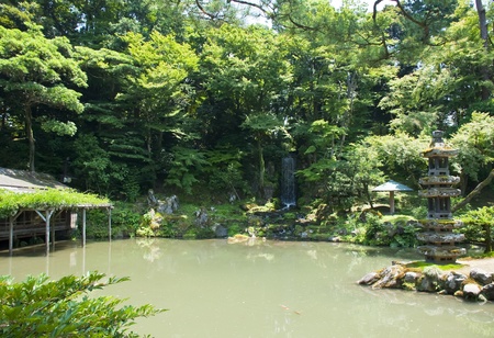 Japanese lake with a waterfall and one of the famous lanternsの写真素材
