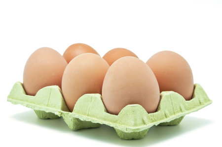 Six raw eggs in an egg cup on white background