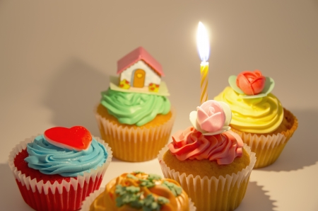 Several colorful cupcakes with a candleの写真素材