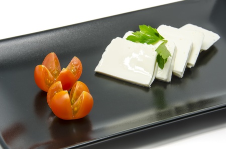 Fresh cheese with cherry tomatoes on a black dishの写真素材