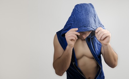 Muscular young man with blue hood on white backgroundの写真素材
