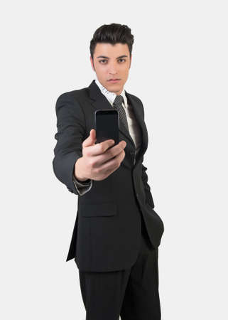 Fashion young man with mobile phone wearing suit and tie on white backgroundの写真素材