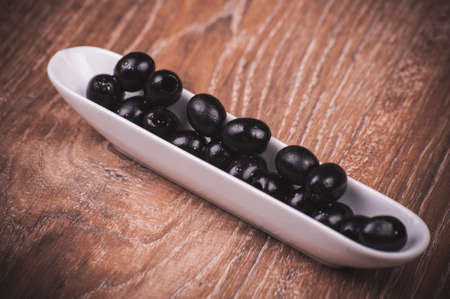 black olives without bone in white plateの写真素材