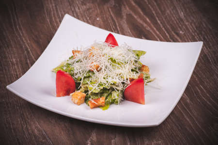 vegetarian cesar salad with tomato, croutons and cheese on white plateの写真素材