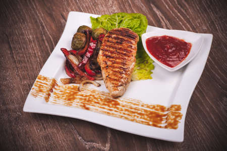 Grilled fillet of chicken with vegetables and sauceの写真素材