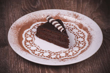 Chocolate cake slice on white plate with cacaoの写真素材