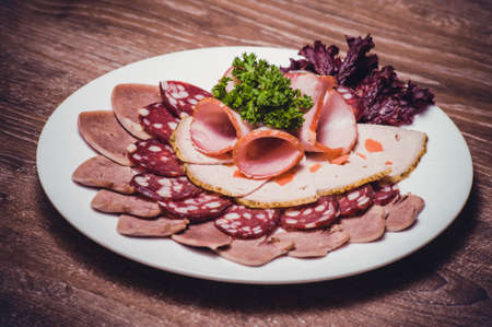 cut meat platter on white plate with greensの写真素材
