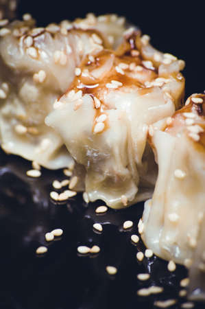 fried gyoza dumplings with sauce on black plateの写真素材