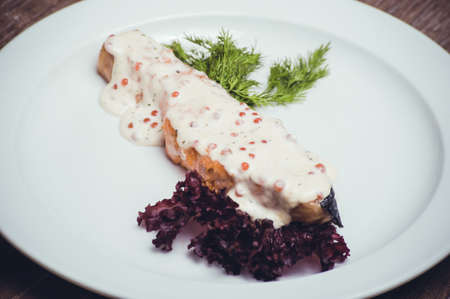 salmon fillet with caviar cream sauce on white plateの写真素材