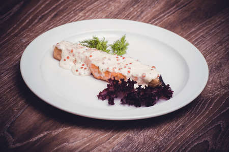 salmon fillet with caviar cream sauce on white plateの写真素材