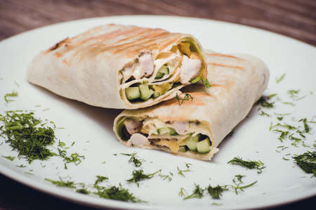 chicken and avocado fried wrap on white plateの写真素材