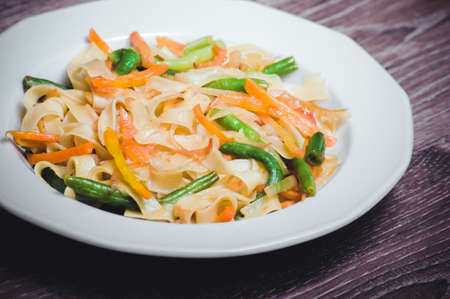 vegetarian pasta with carrot, zucchini on white plateの写真素材